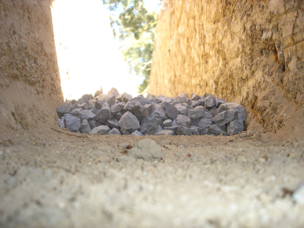 Narrow excavated trench with a stone bed