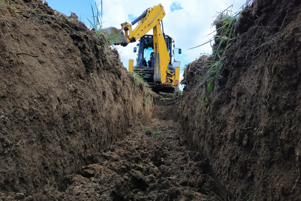 Excavated trench with a backhoe at the far end; illustrative service photo